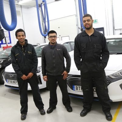 students infront of cars in workshop