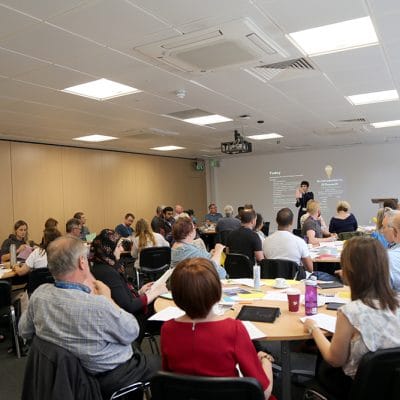 conference event full with people and a speaker at the front