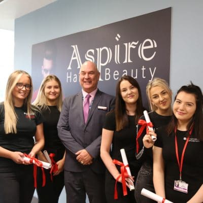 Hair & beauty students with principal holding scrolls
