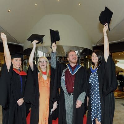 Students celebrating at graduation with hats above head