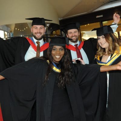Students celebrating at graduation with arms in the air