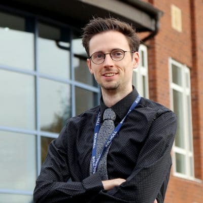 Male stood with crossed arms outside a building
