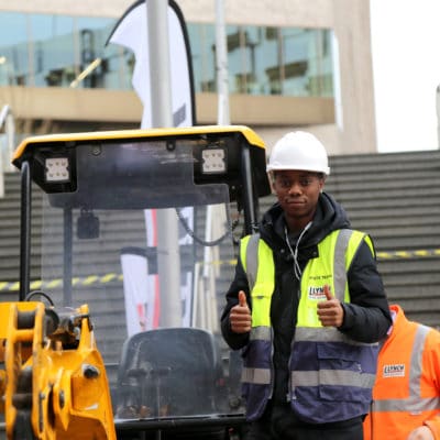 a student stands in front of a plant machine
