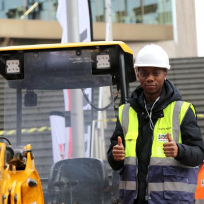 a student stands in front of a plant machine