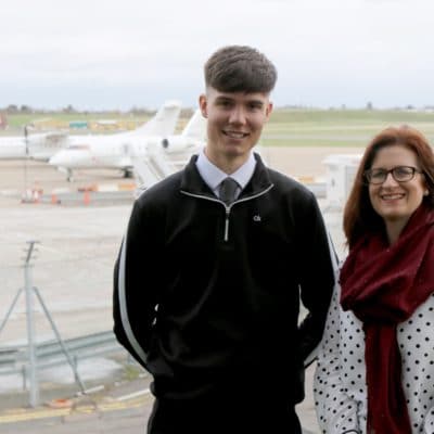 Joe stands with Jane in front of aircrafts at airport