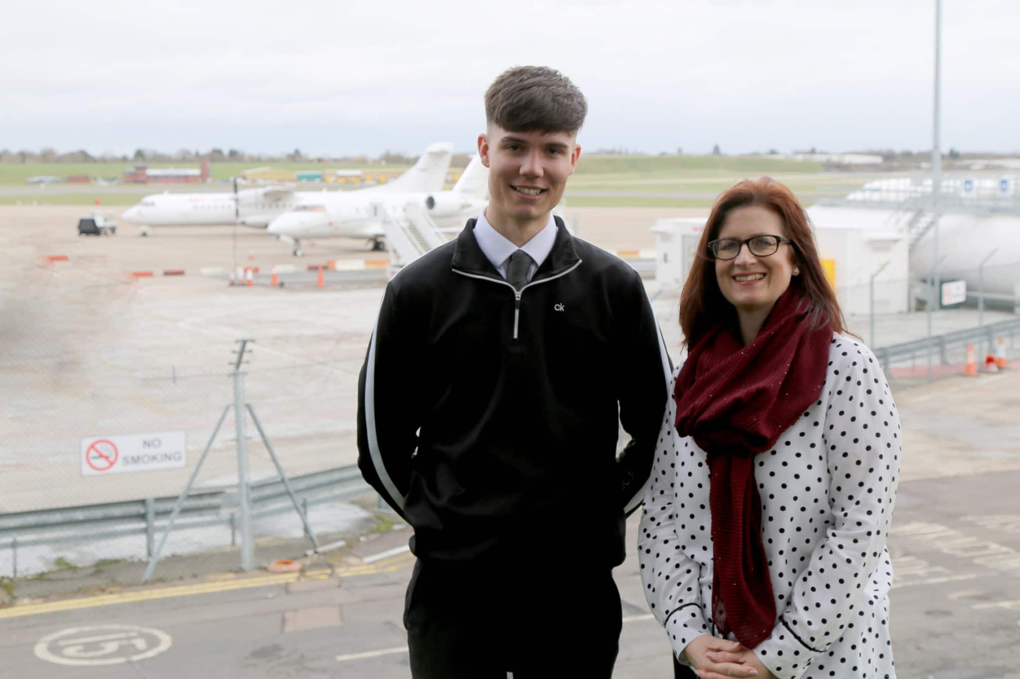 Joe stands with Jane in front of aircrafts at airport