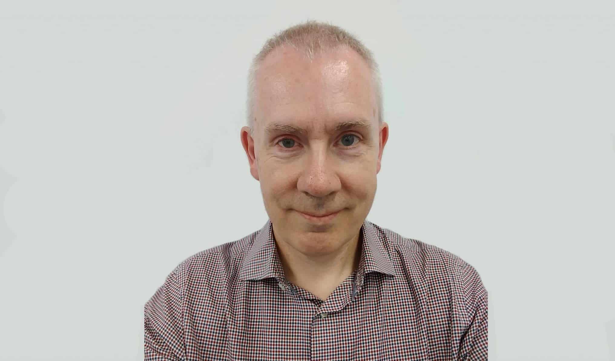 Paul Hanna stood in front of a grey wall.