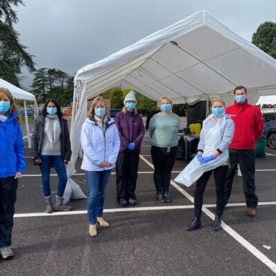 A group of attendees including staff standing in masks in the car park.