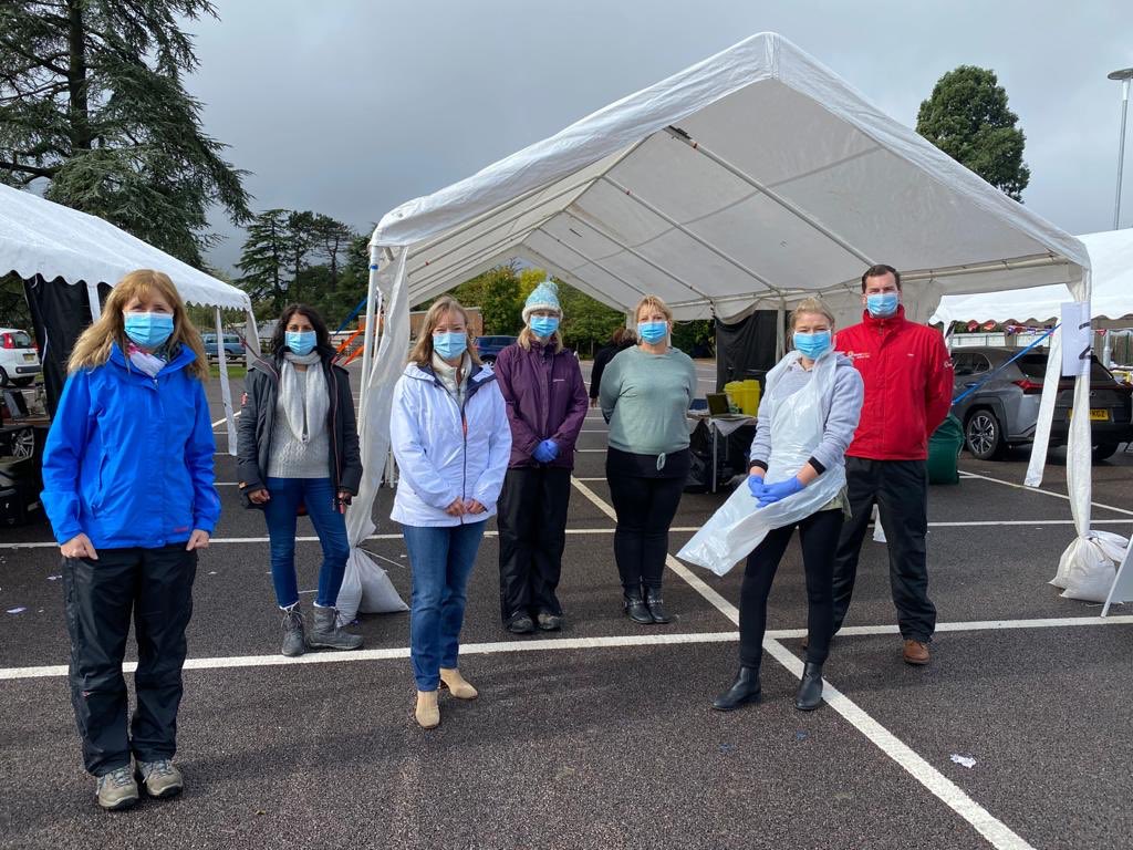 A group of attendees including staff standing in masks in the car park.