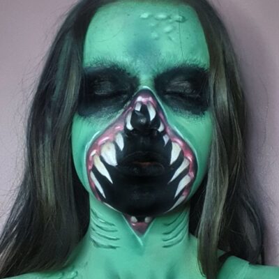 a student is painted neon green with a gaping toothed mouth across most of her face