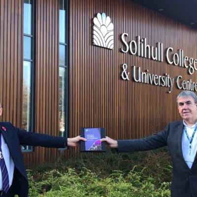 Mick Westman stands receiving the award outside the college with Robert Elliot, President of the Solihull Chamber of Commerce.