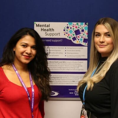 Fathima and Blair stand in front of a Mental Health Poster