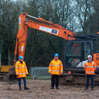 the group stand in PPE in front of plant machinery.