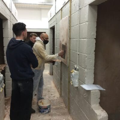 students watch a male tutor plaster the wall