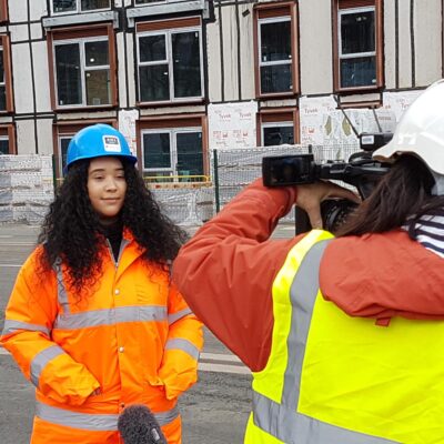 Iman talking to BBC News in a blue hard hat on the construction site.