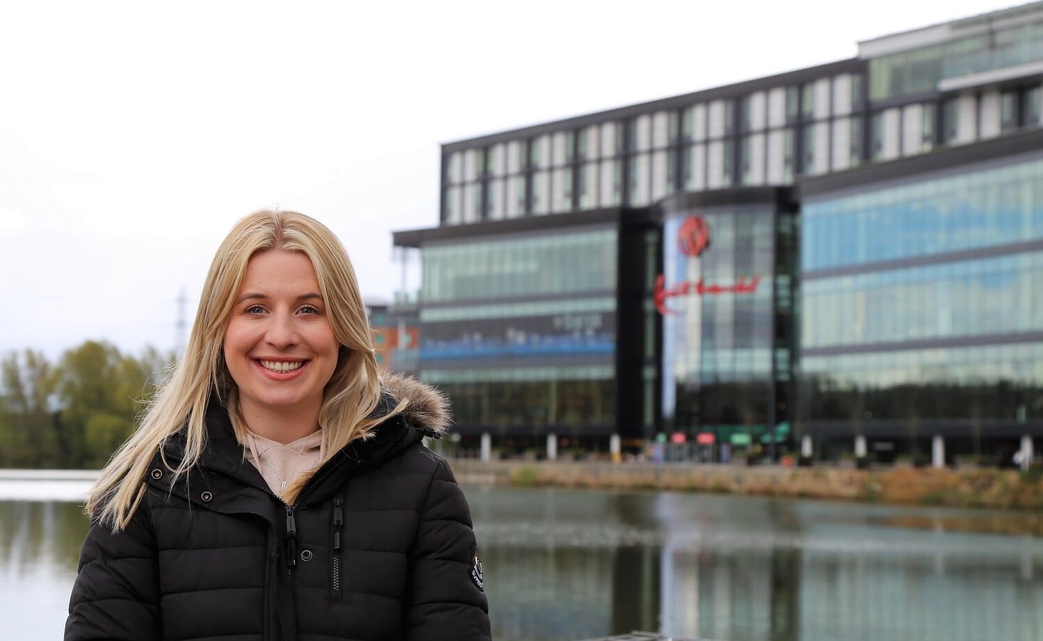 Annabelle stands in a coat in front of Resorts World next to a lake.
