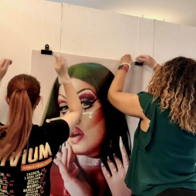 two artists hanging up a portrait on the wall in the art foyer