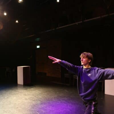 Cameron in the theatre arms outstretched under the lights