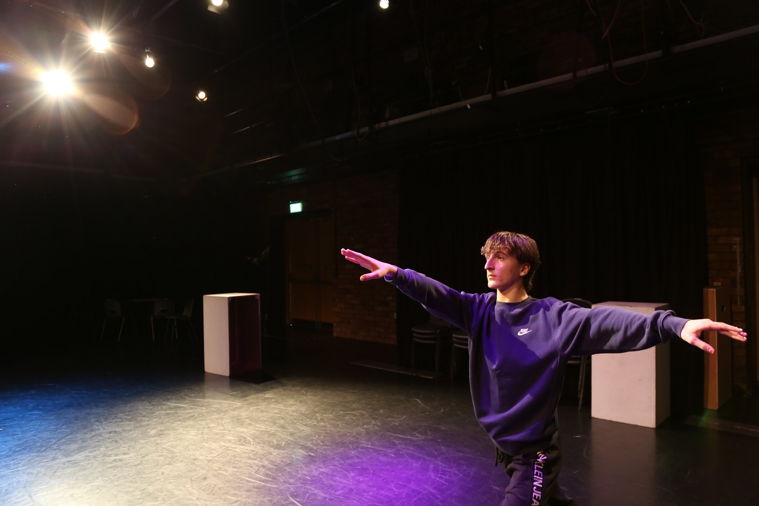 Cameron in the theatre arms outstretched under the lights