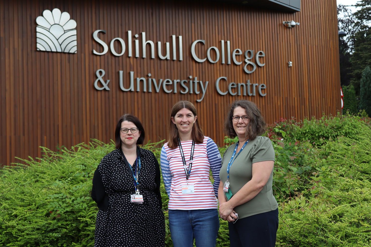 Kerry Scattergood with contributors Isla Flood and Carol Baker stood outside the College with the sign behind them