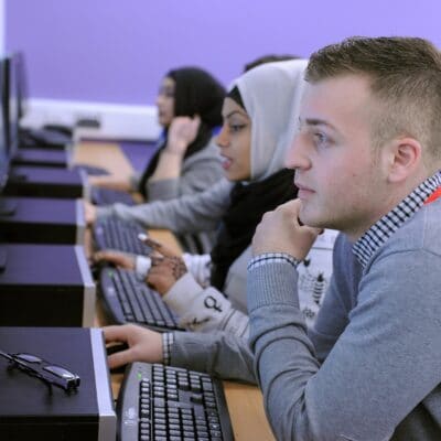 A male students sits studying on campus in front of his computer