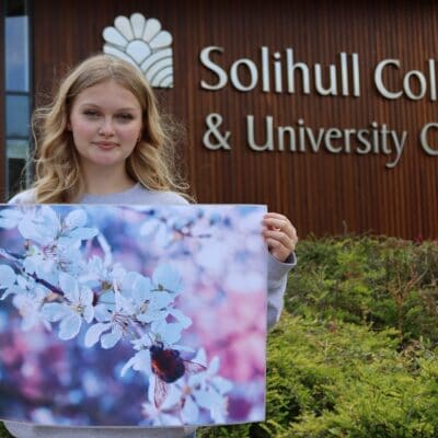 Hattie holding her winning bee image print outside of college.