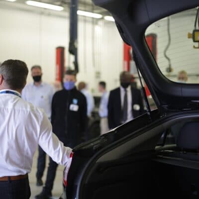 Alan leans next to the boot of the car talking to attendees whos faces are out of focus