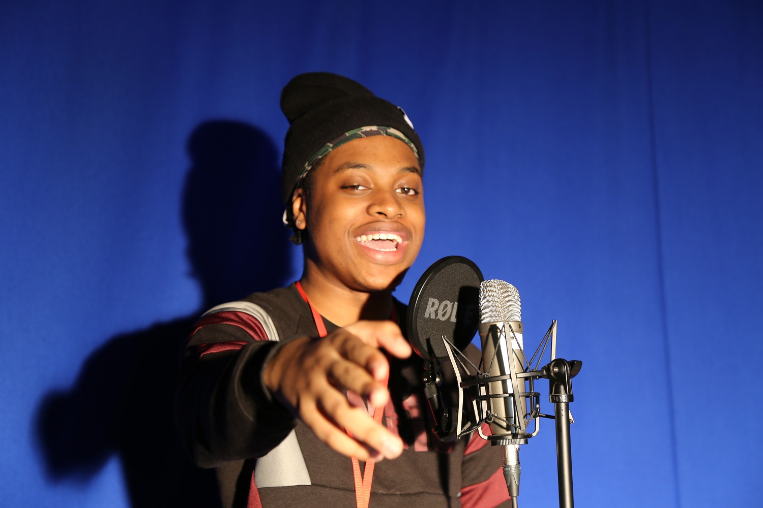 Remar stands in front of a mic in a media studies studio
