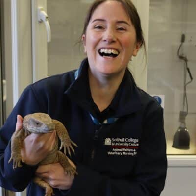 Tutor holding lizard and smiling