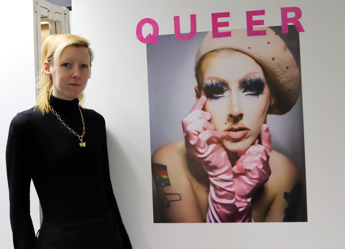 student standing in front of self portrait with 'Queer' written in pink