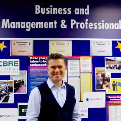Hakan standing in front of board that reads Business and Management & Professional at the top