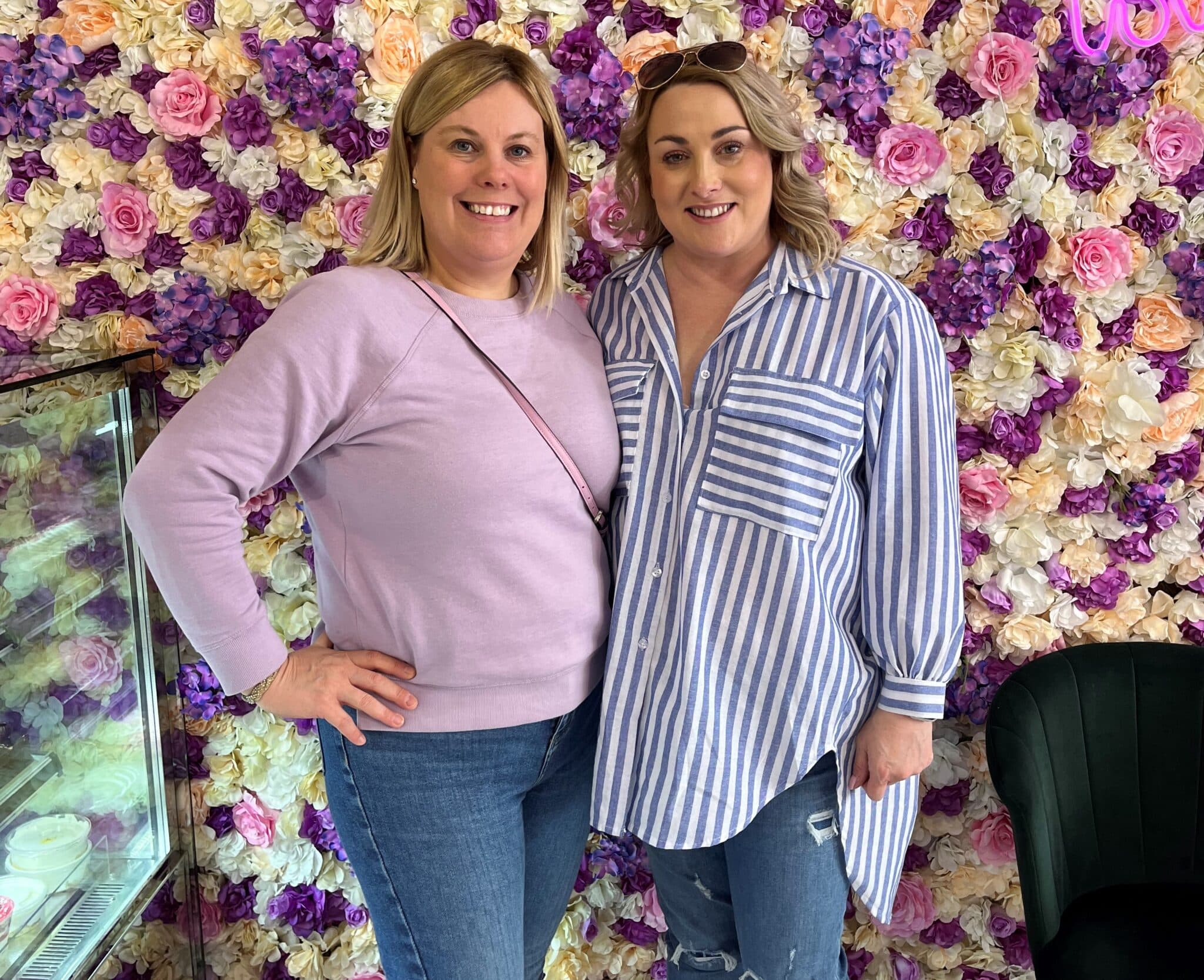 Make up students in front of flower wall