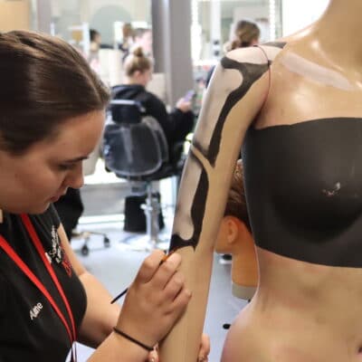 Student painting on mannequin