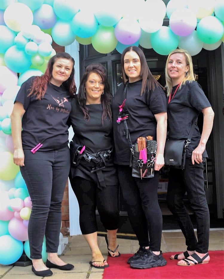4 students standing with balloons behind them