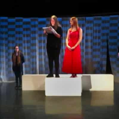 5 students standing on stage for rehearsal