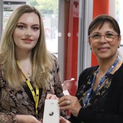 Student and staff standing holding apple air tag