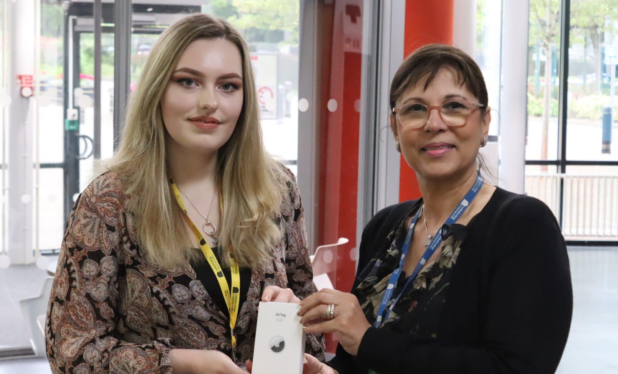 Student and staff standing holding apple air tag