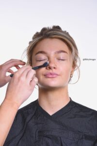 woman applying make up with brush on face