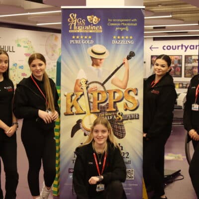 students wearing black standing in front of KIPPS promotional banner