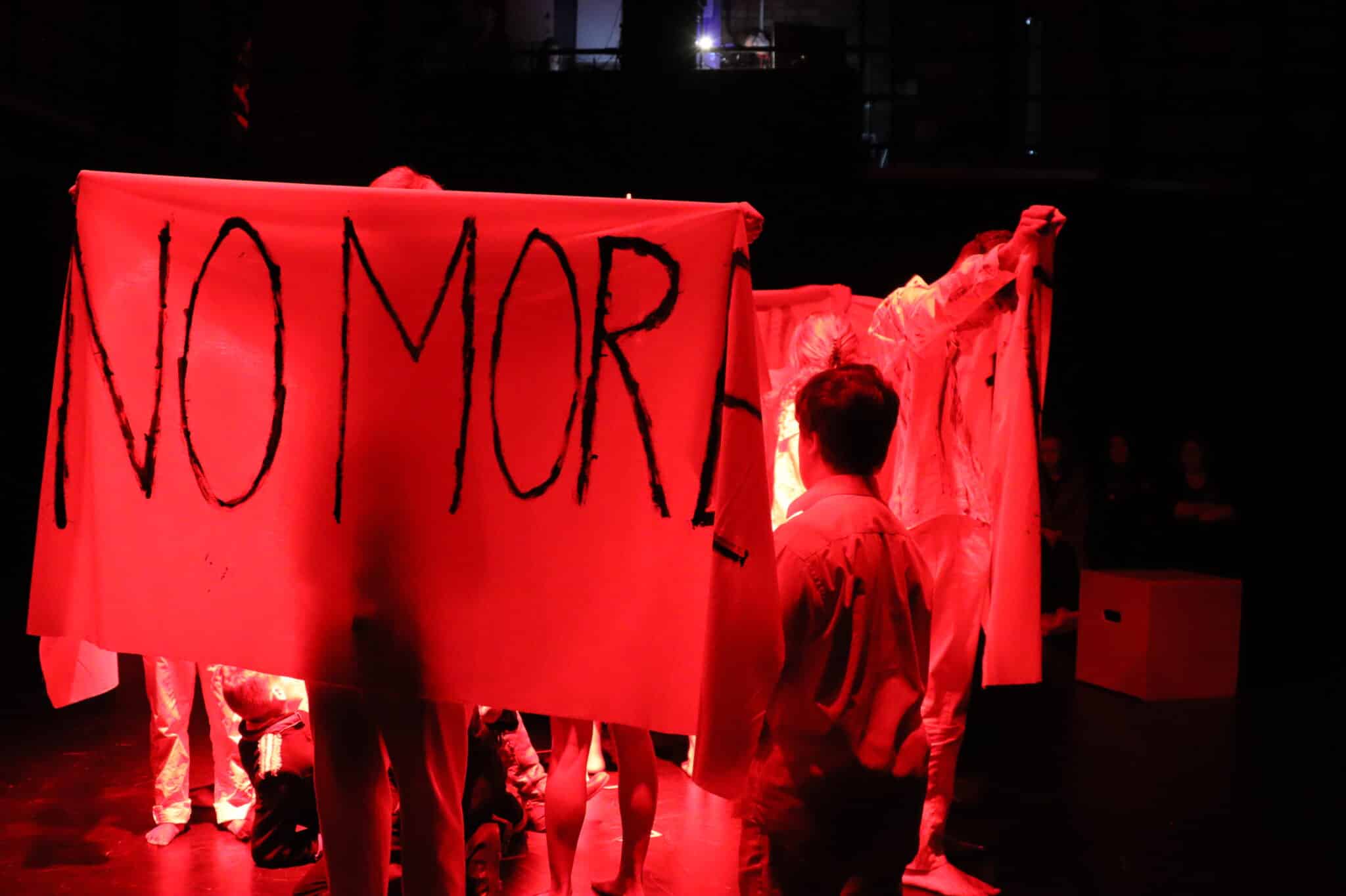 Banner held up in red light that says 'no more'