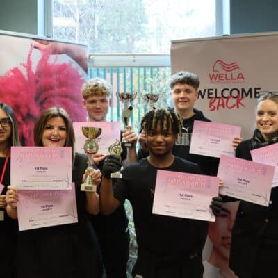 Group photo of Barbering team winning big- certificates and cups held