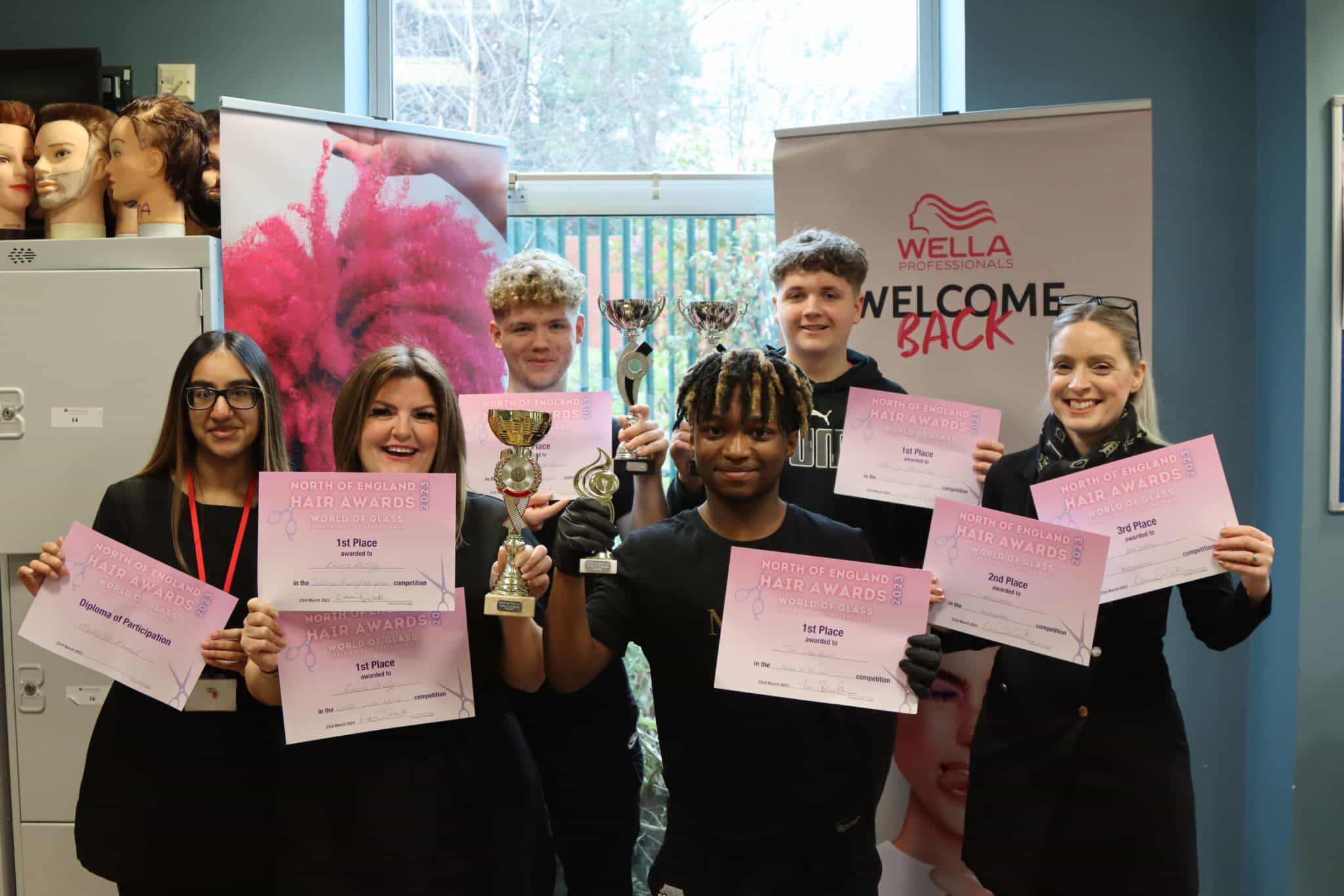 Group photo of Barbering team winning big- certificates and cups held