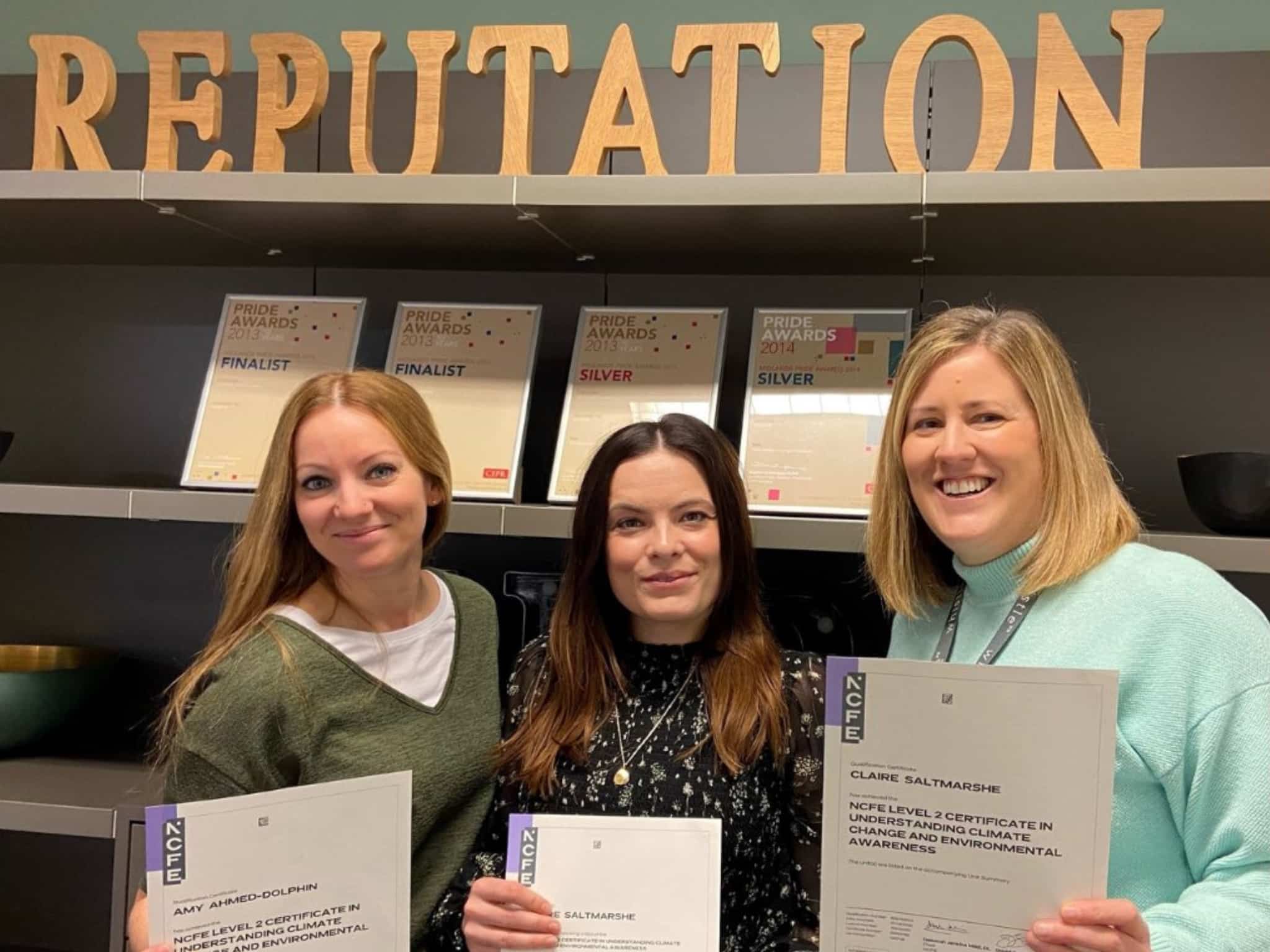 3 people standing holding certificate