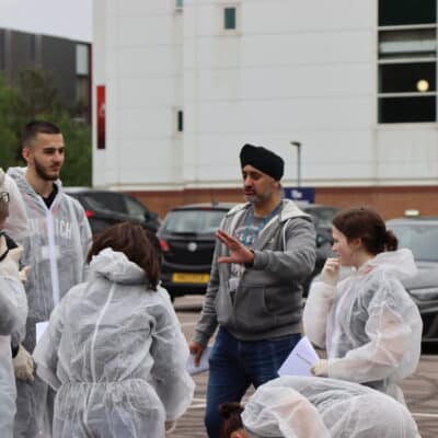 Lecturer talking to students outside during forensic road traffic accident simulation.