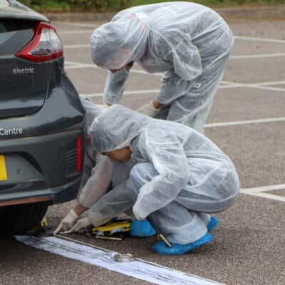 Students pointing at evidence for a forensic investigation re-enactment by the college.