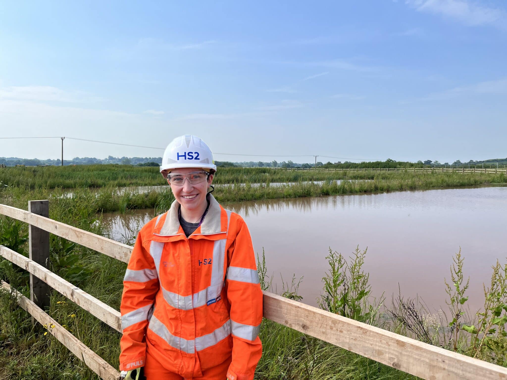 Alice wearing orange hi vis jacket and hard hat at HS2 site