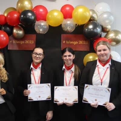 students standing in front of balloons with their certificates