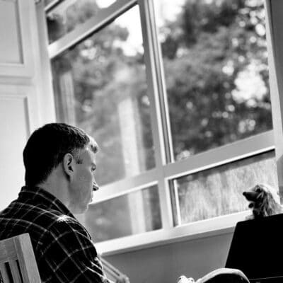 Richard sitting at his computer in front of a window