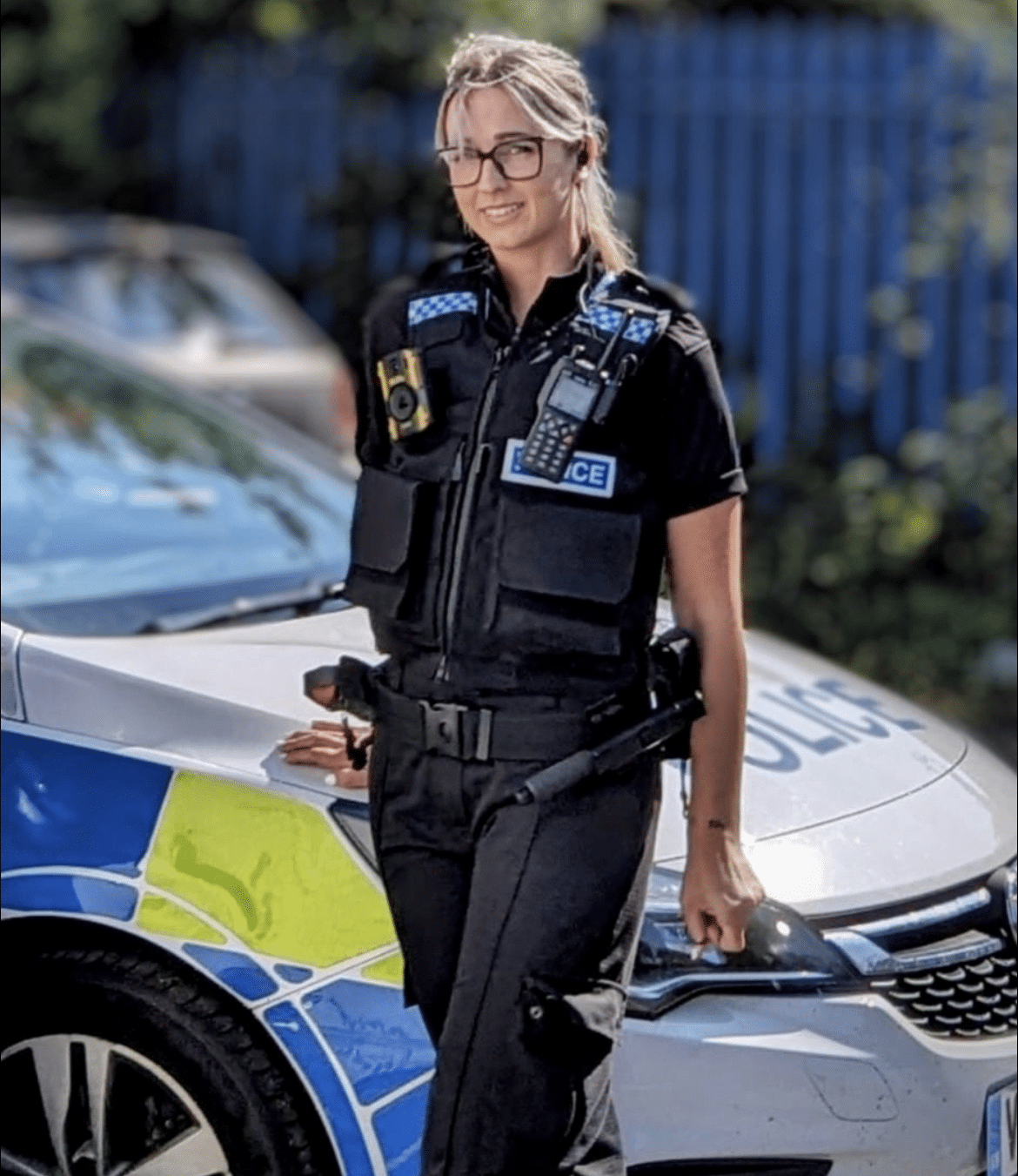 Heather in uniform standing by the police car