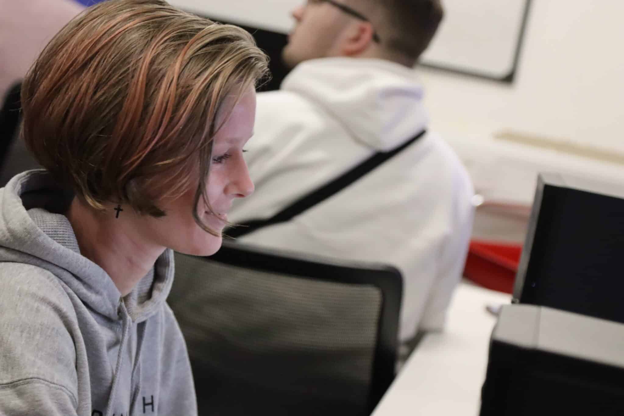 student sat in front of computer smiling